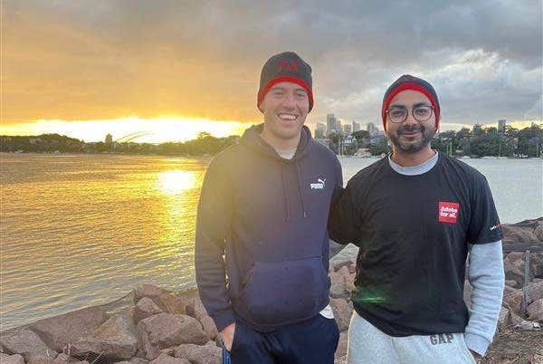 Two men standing with the sun set behind them.