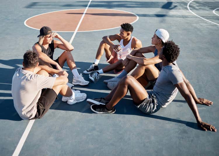 Image of a group of people sitting on a basketball court.