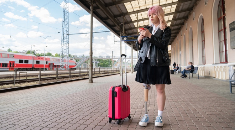 Girl standing outside a train station wearing a prosthetic leg.