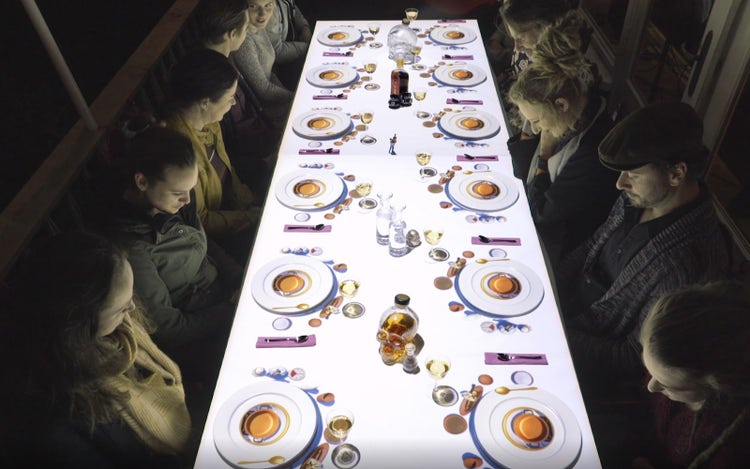 Image of a table full of people and plates of food from Le Petit Chef.