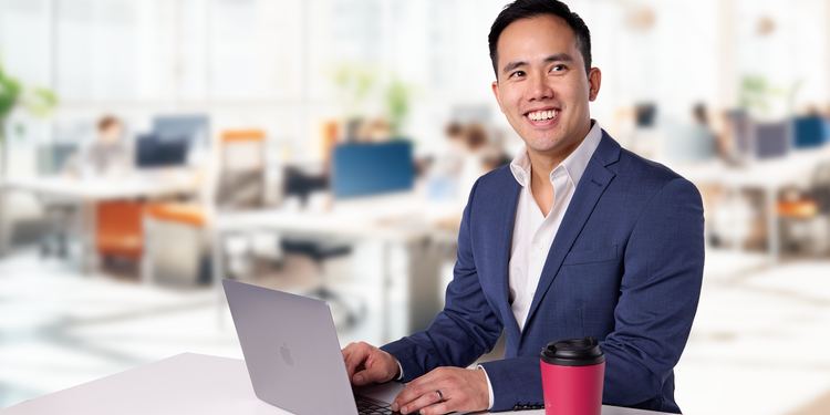 David Chung (Asian, man), sitting in front of his laptop, smiling.