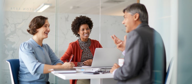 Three people meeting around a desk.