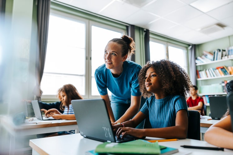 Teacher helping her student with a laptop.