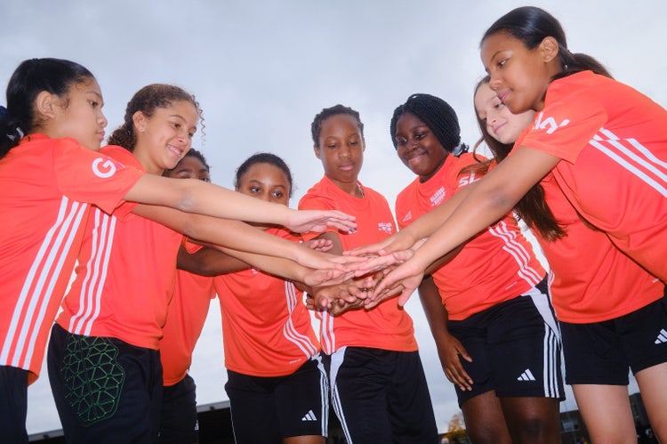 A group of girls in uniform putting their hands together AI-generated content may be incorrect.