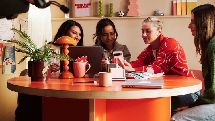 A group of women sitting at a table looking at a computer AI-generated content may be incorrect.