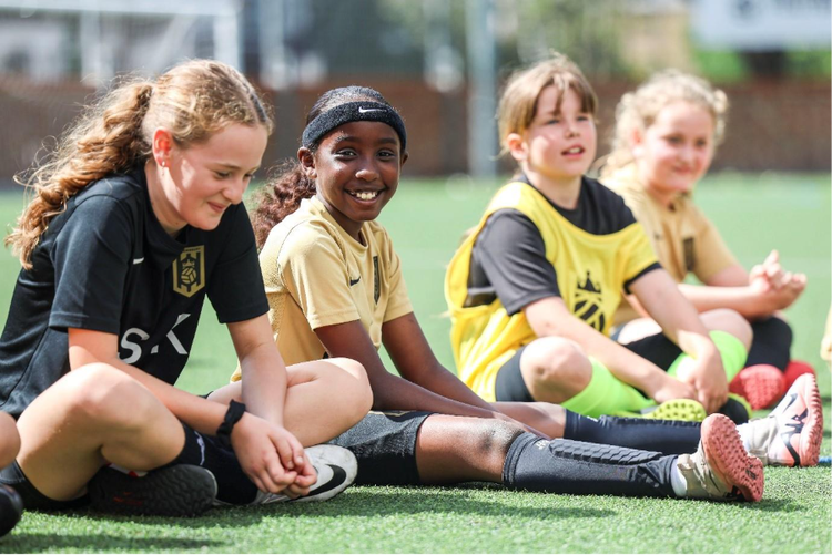 A group of girls sitting on a field AI-generated content may be incorrect.