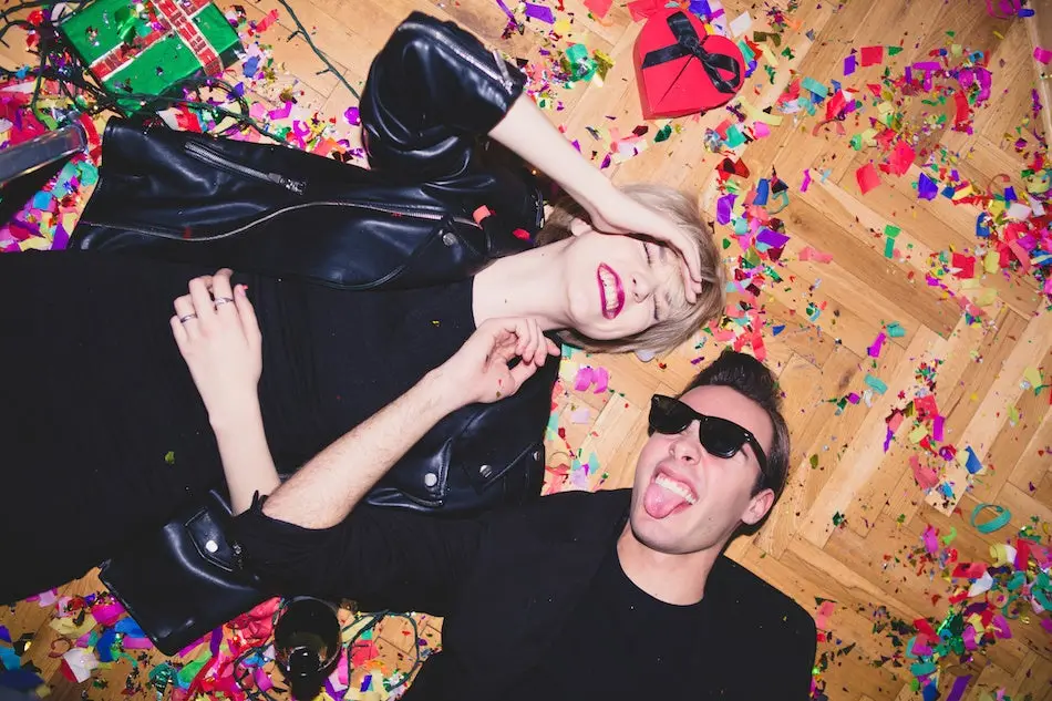 Girl and boy laying on the floor full of confetti