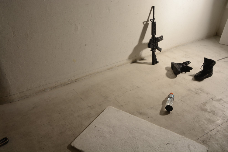 imagen de un arma recostada sobre una pared blanca