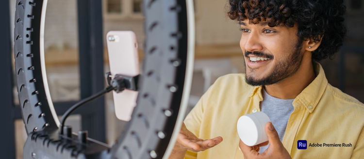 Foto de un hombre con camisa amarilla grabando un video con su celular dentro de su casa