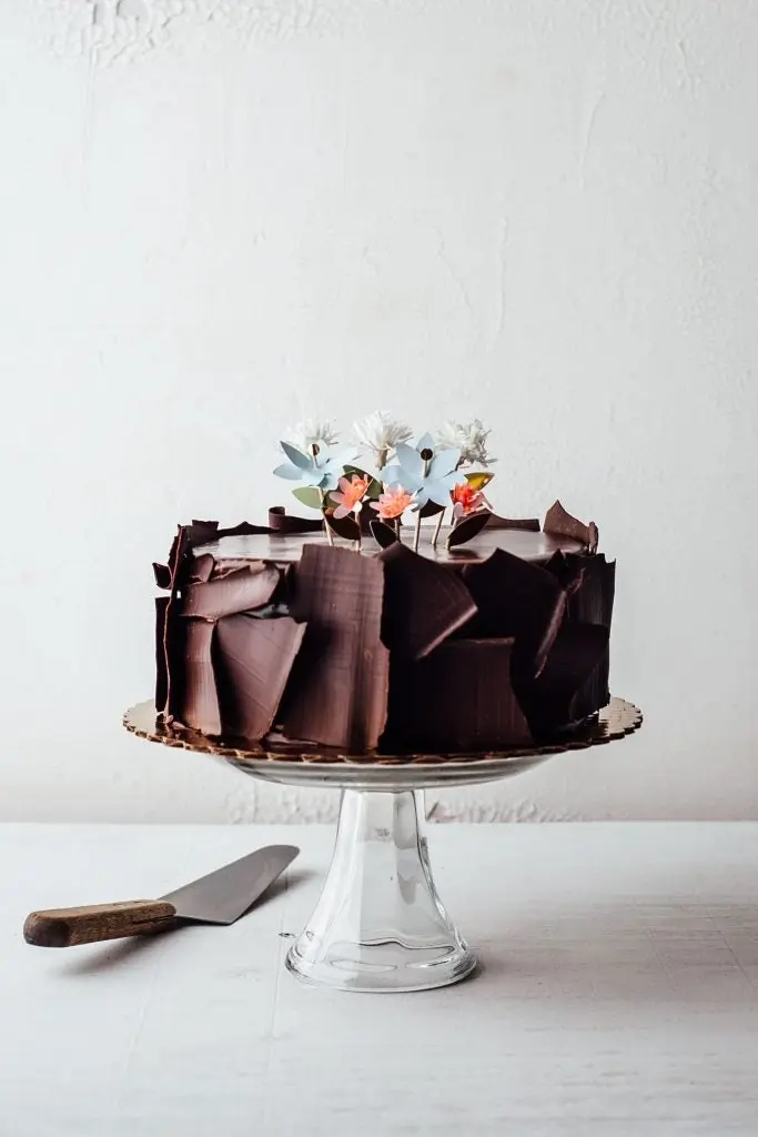 torta de chocolate sobre una plataforma al lado un a espatula para escoger porciones de la torta 