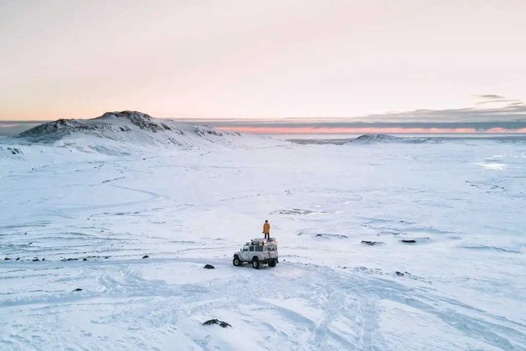 jeep en medio de un desierto de hielo con una persona sobre el 