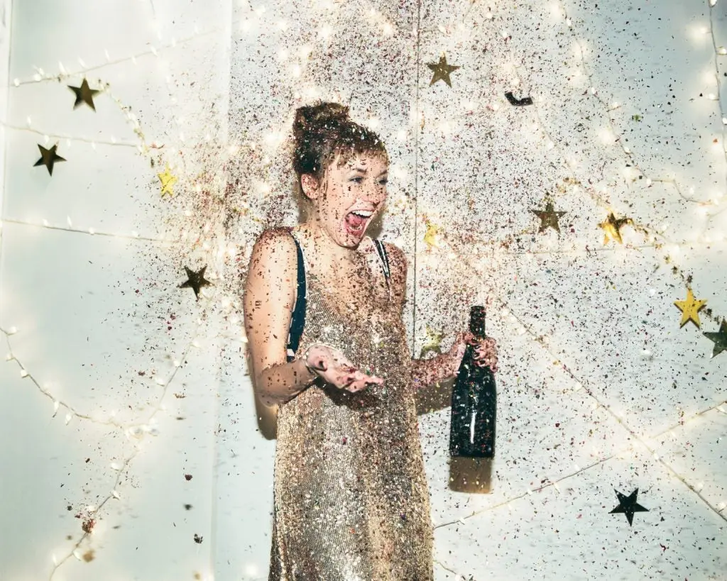 mujer joven feliz celebrando con una botella de champan en su mano 