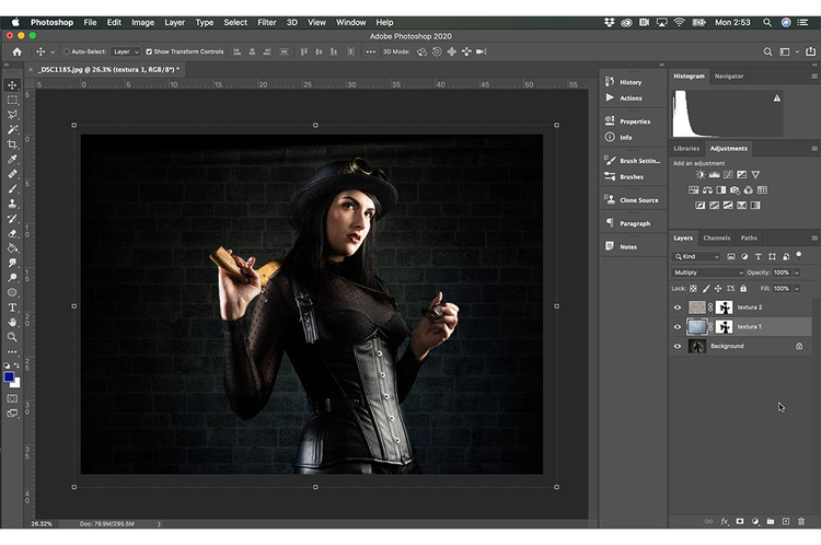 interfaz de Photoshop en ejecucion la imagen de una mujer vestida de negro sosteniendo un arma en su hombro y un collar en su otra mano detras un fondo de ladrillo