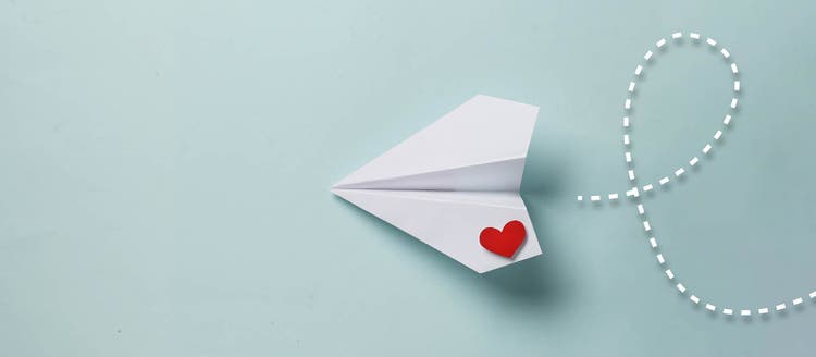 ilustracion de un avion de papel con un corazon rojo en una de sus alas