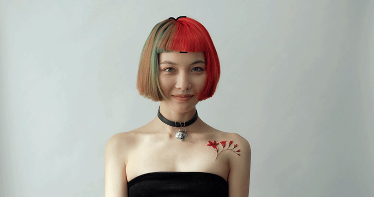 Fotografia de una mujer joven sonriendo con su cabello pintado de colores y un tatuaje de rosas en su hombro 