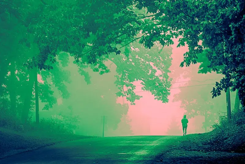Fotofragia con sombras y luces verdes de una persona caminando por una calle solitaria, gradiente de color 