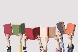 brazos de cuatro estudiantes extendidos cada uno con un libro en sus manos