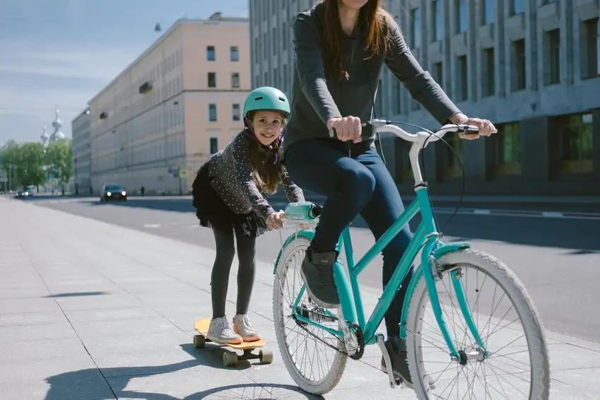 Mother and daughter ride a scooter and bicycle together