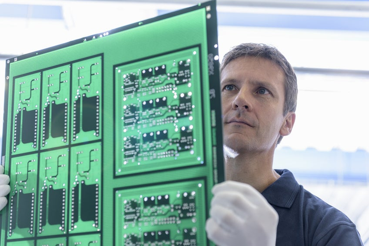 Worker inspecting circuit board during manufacture in circuit board factory