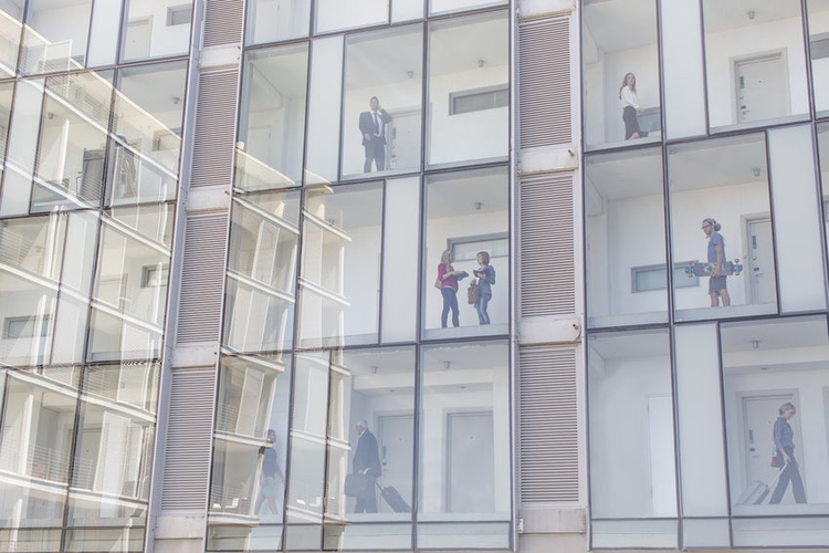 Guests in above and below corridors of glass fronted hotel