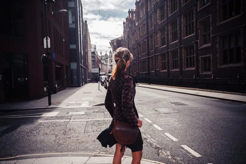 A young woman is walking in the street and is looking at the architecture