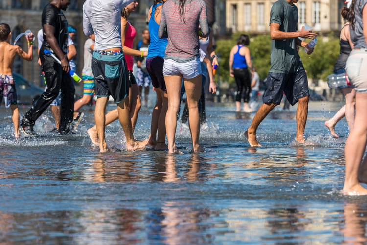 People having fun in a mirror fountain in front of Place de la Bourse in Bordeaux, France