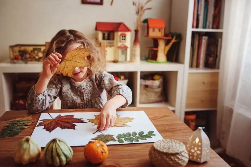 cute child girl making herbarium at home, autumn seasonal crafts