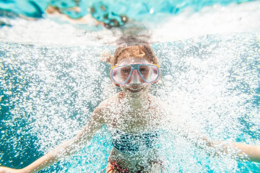 9 years old child wearing diving mask swimming in the pool, underwater shot