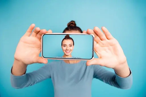 Una donna sorride mentre si fa un selfie