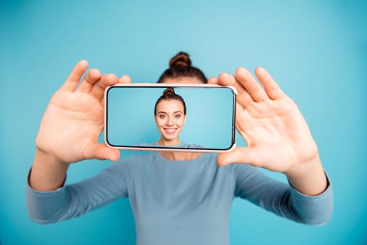 Una donna sorride mentre si fa un selfie