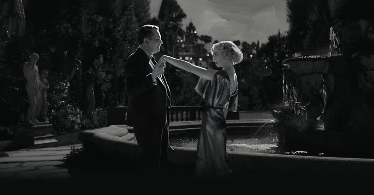 Black and white photo showing a man and woman dancing. 