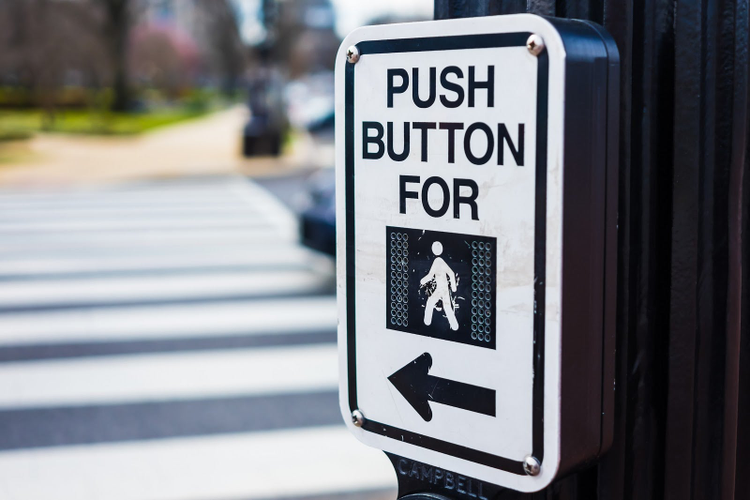 信号を作動させるために歩行者にボタンを押すよう促す横断歩道の信号標識。