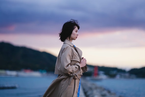 雪が降った山の前に立っている女性 中程度の精度で自動的に生成された説明