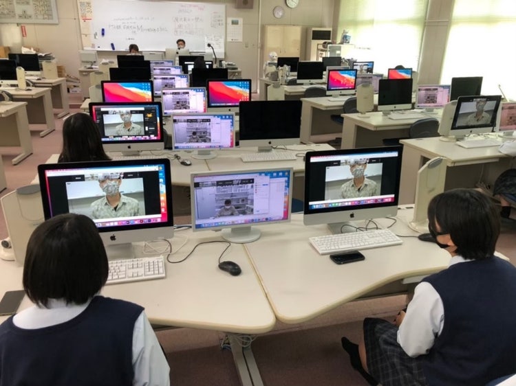 机の上でコンピューターを使っている人達 中程度の精度で自動的に生成された説明