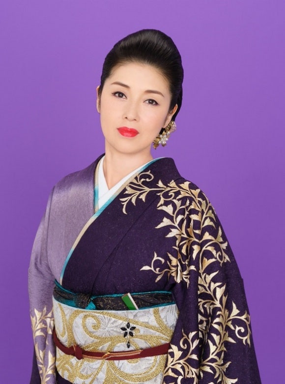 白いバックグラウンドの前に立っている女性 低い精度で自動的に生成された説明