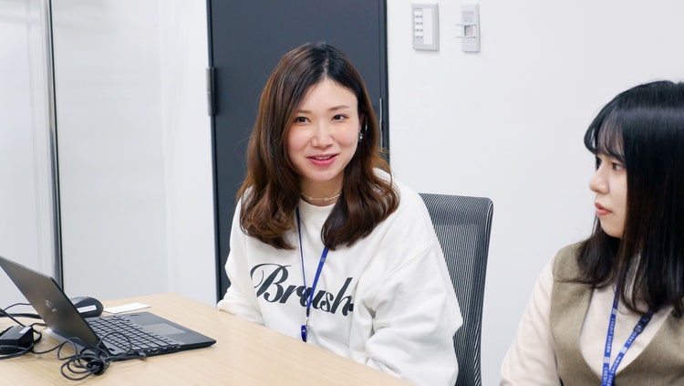 机の上のパソコンと女性 自動的に生成された説明