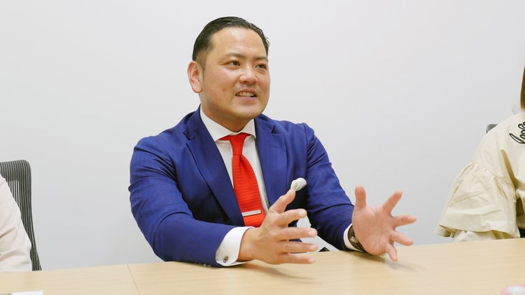 ネクタイをして座っている男性 自動的に生成された説明