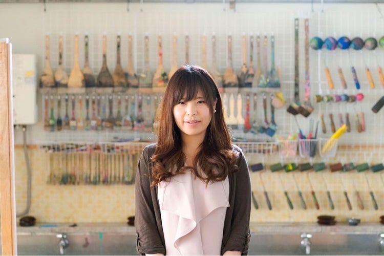 A person standing in front of a wall with art on it Description automatically generated with low confidence