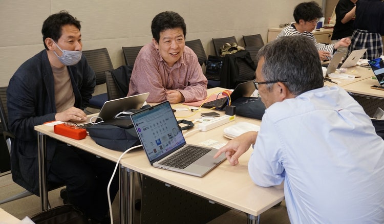 ノートパソコンで作業をしている人たち 自動的に生成された説明