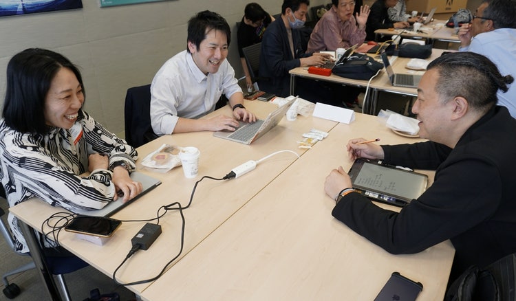ノートパソコンで作業をしている人たち 中程度の精度で自動的に生成された説明