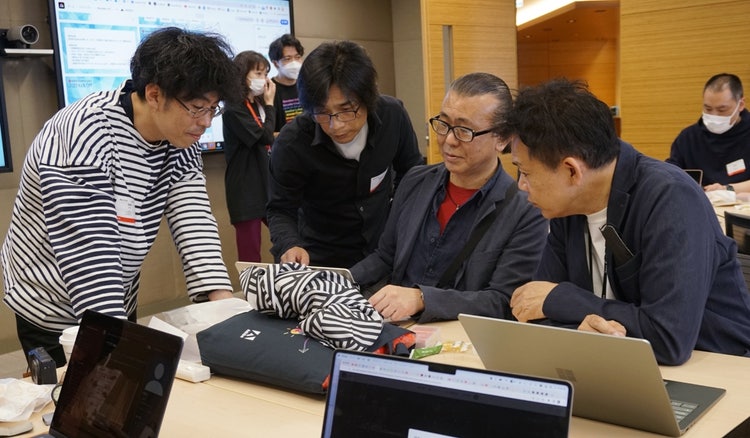 ノートパソコンで作業をしている人たち 自動的に生成された説明
