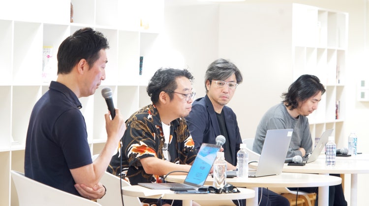A group of people sitting at tables with laptops Description automatically generated