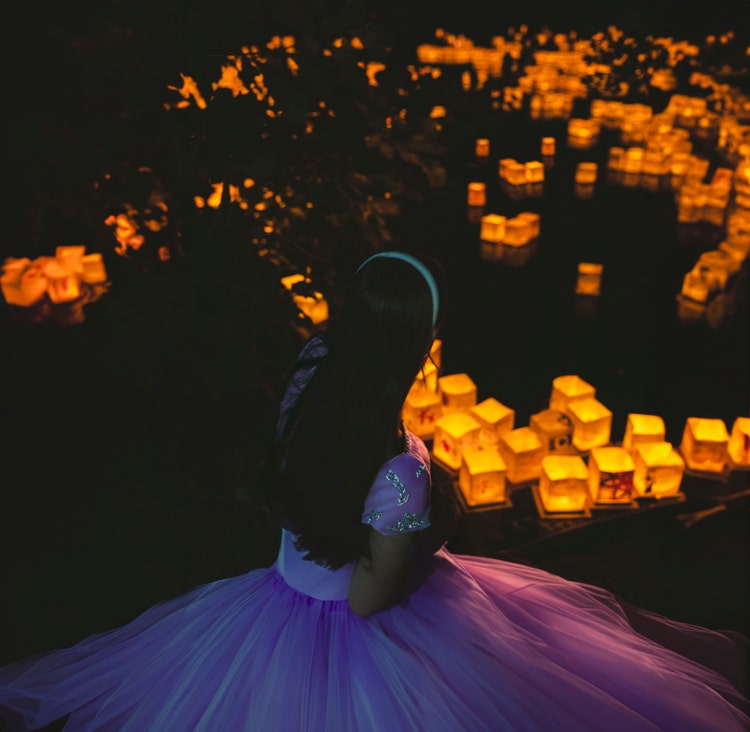 Adobe Firefly を使用した後の、明かりの灯るランタンに囲まれた少女の画像。