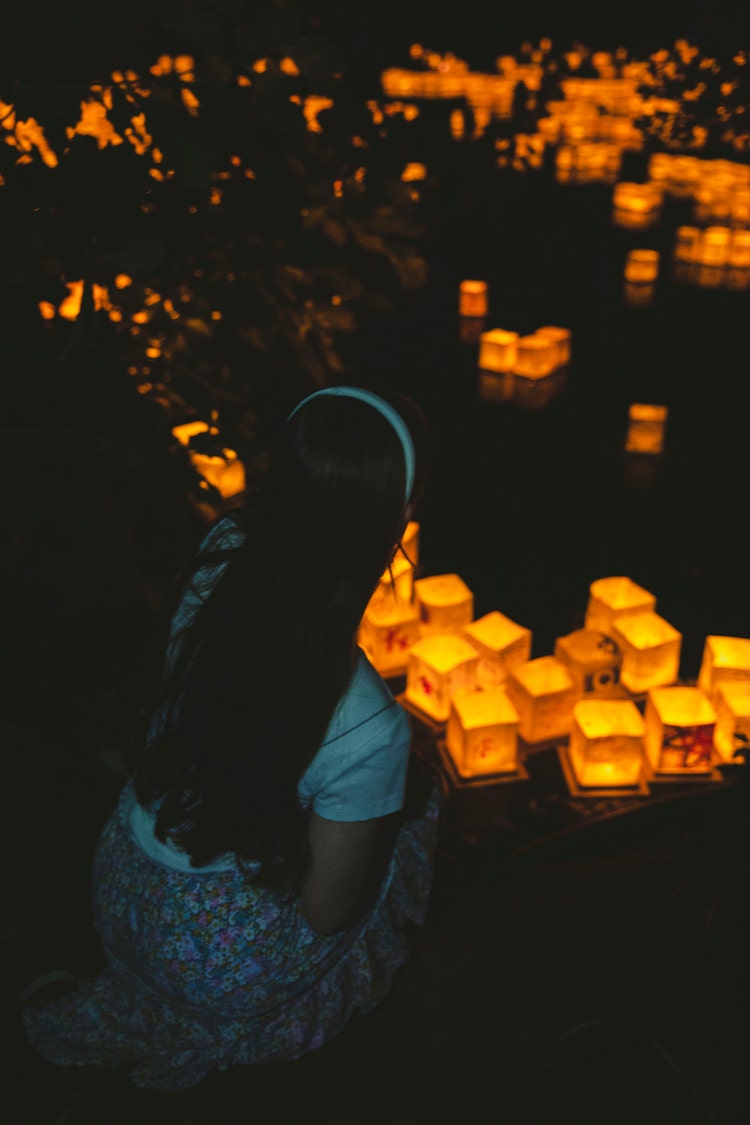 明かりの灯るランタンに囲まれた少女の画像。