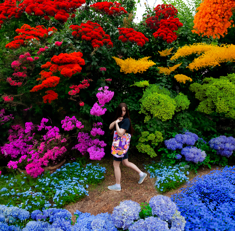 Adobe Firefly を使用した後の色とりどりの植物に囲まれたバッグを持つ少女の画像。