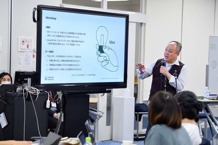 コンピューターの前に立っている人たち 低い精度で自動的に生成された説明