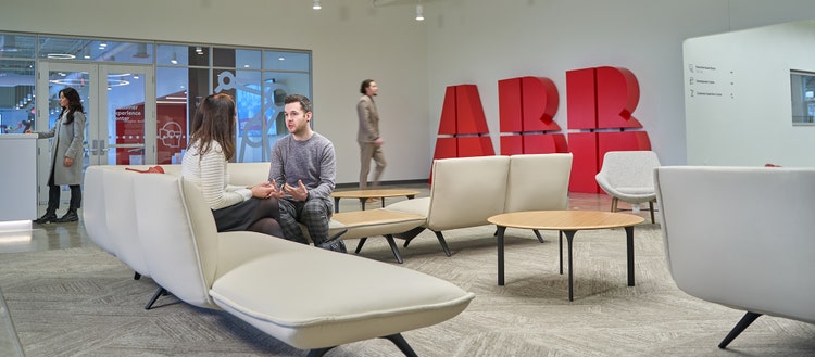ABB オフィスのソファに座って会話する 2 人の写真。