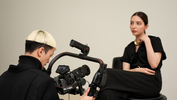 スーツを着ている人は座っている 自動的に生成された説明