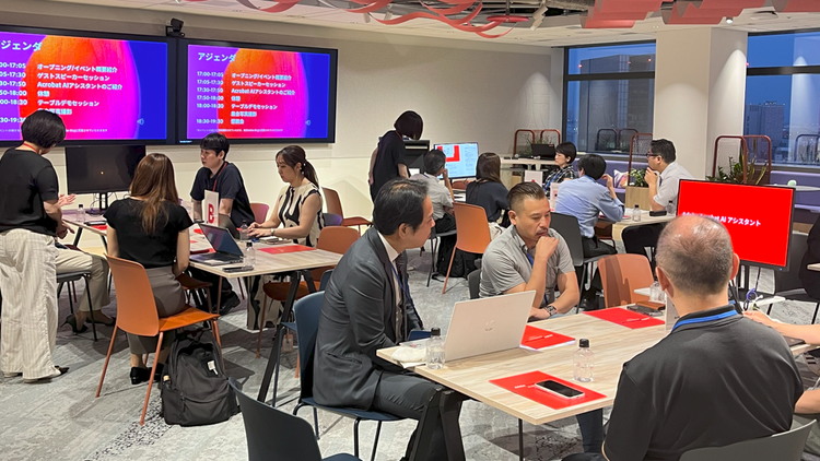 A group of people sitting at tables in a room with computers AI-generated content may be incorrect.