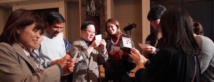 ビンゴ大会でカードを確認しながら盛り上がる参加者の写真です。あ、リーチ！